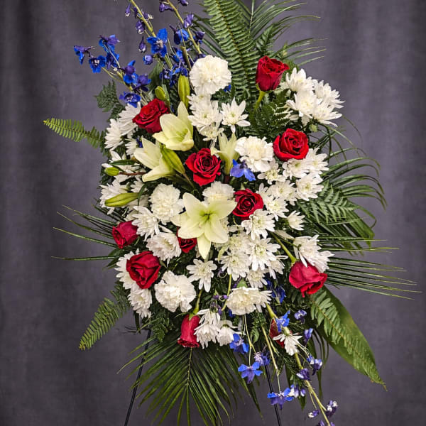 Standing floral spray with red roses, white lilies, and blue flowers