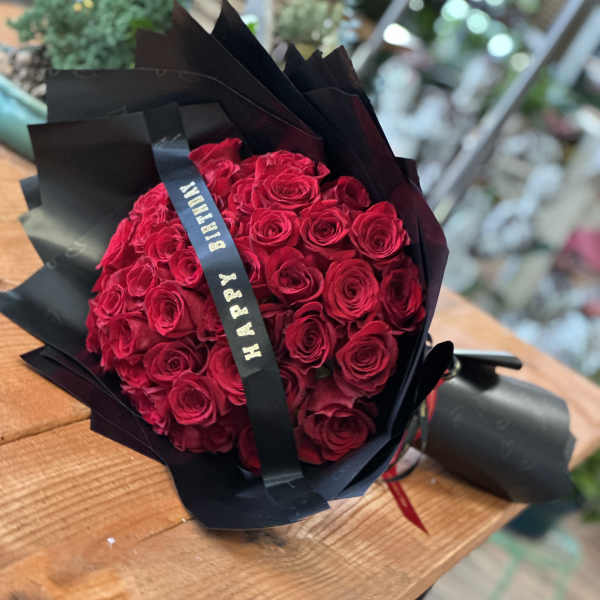 Bouquet of red roses wrapped in black paper with a ribbon