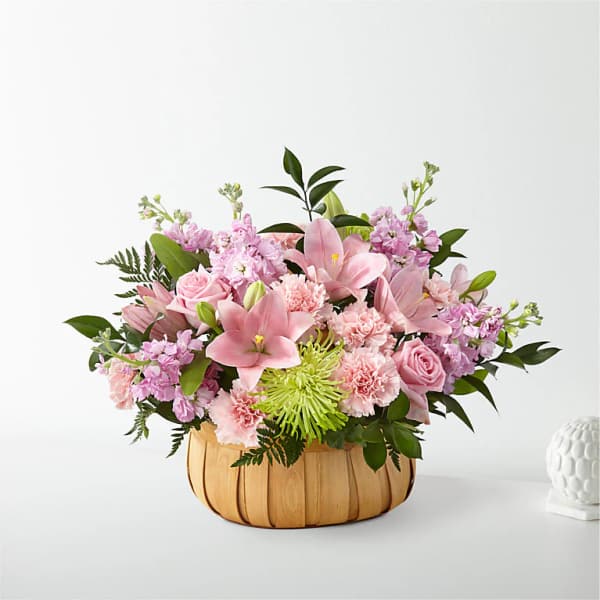 Pink floral arrangement in a woven basket with lilies and roses
