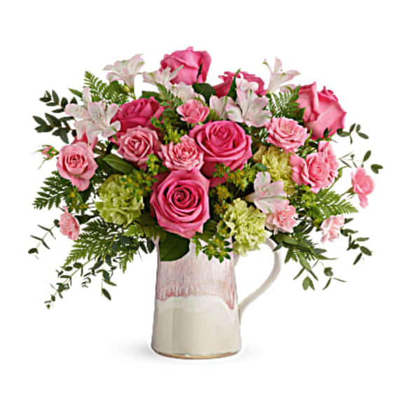 Pink roses and lilies arranged in a ceramic pitcher vase