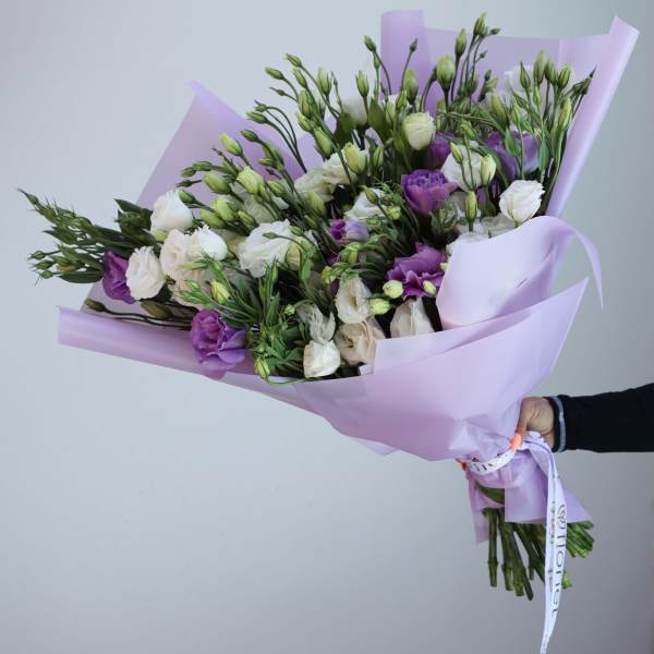Bouquet of white and purple flowers wrapped in lavender paper