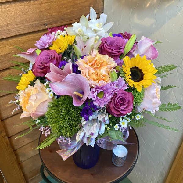 Mixed bouquet with sunflowers, roses, lilies, and calla lilies in a vase