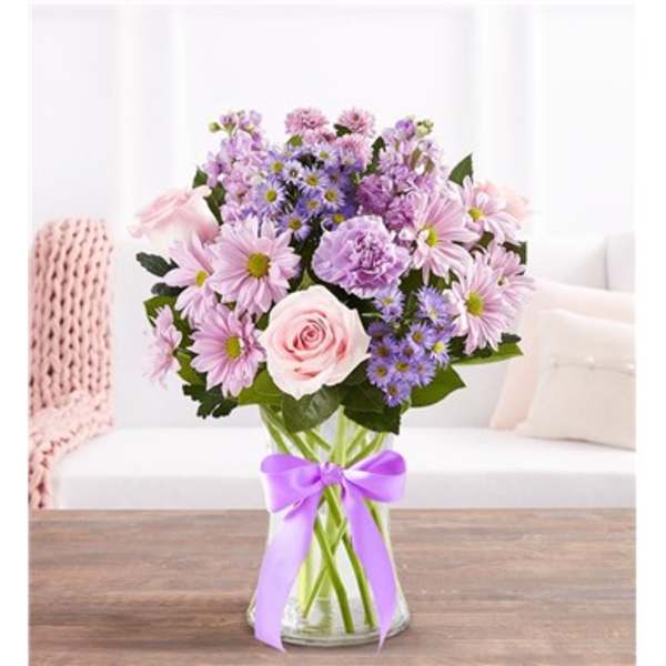 Pink and lavender bouquet in a clear glass vase with a purple ribbon