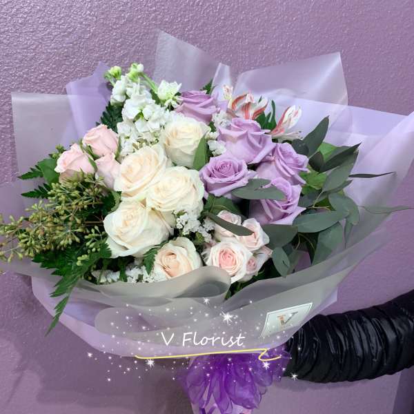 Bouquet of lavender and cream roses with pink flowers in purple wrap