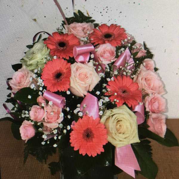 Pink and coral bouquet with roses and gerbera daisies in a glass vase