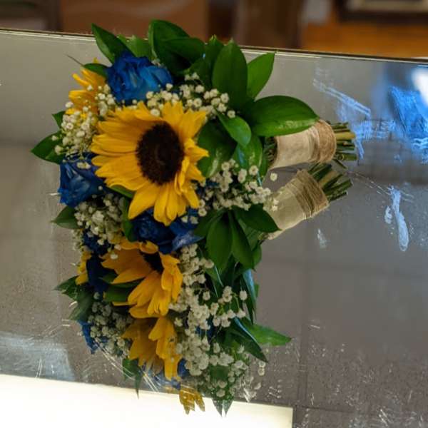 Bouquet of yellow sunflowers and blue roses with white baby's breath