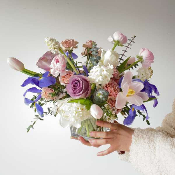 Handheld bouquet of pink, white, and purple flowers in a glass vase