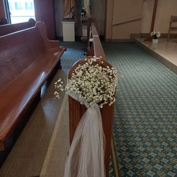 White baby's breath arrangement with sheer tulle draped over a pew