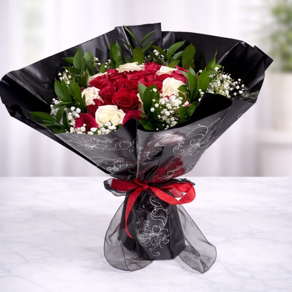 Bouquet of red and white roses wrapped in black paper with a red ribbon