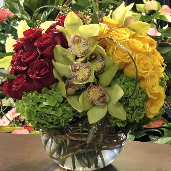 Bouquet of red and yellow roses with green orchids in a glass vase