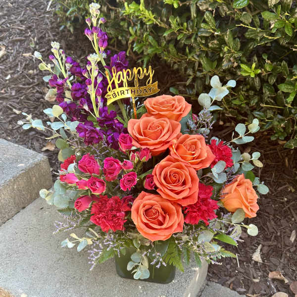 Orange and pink rose arrangement with a Happy Birthday pick in a vase