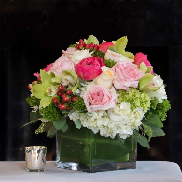 Pink and white floral arrangement in a square glass vase