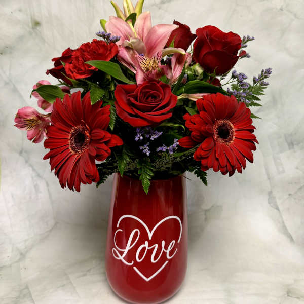 Red and pink mixed bouquet in a red vase with a heart and the word Love