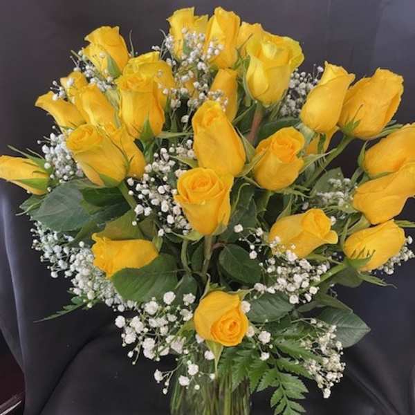 Yellow roses arranged in a clear glass vase with baby's breath