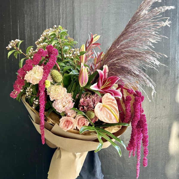 Large bouquet with pink lilies, roses, and pampas grass wrapped in paper
