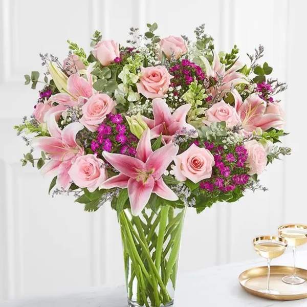 Pink lilies and roses arranged in a clear glass vase