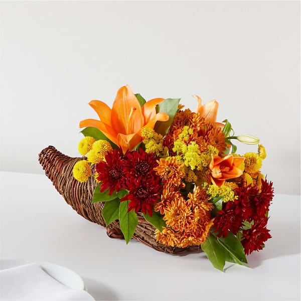 Orange lilies and red chrysanthemums in a wicker cornucopia basket