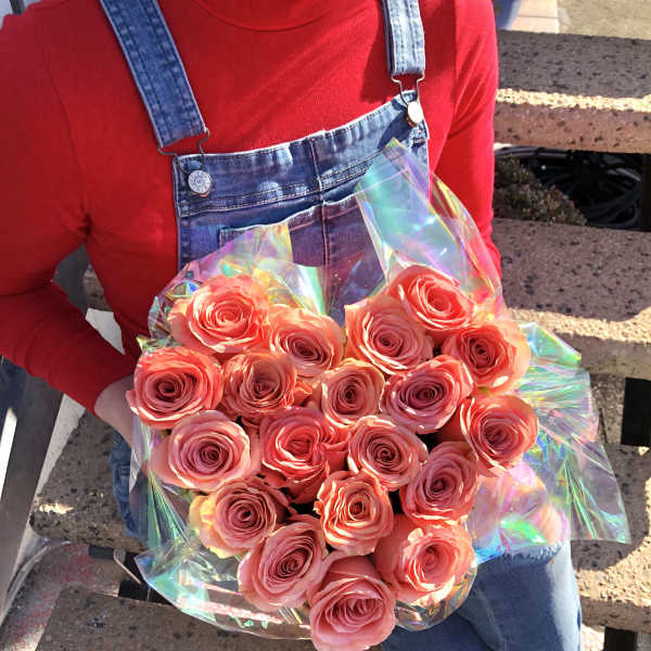 Bouquet of pink roses wrapped in iridescent plastic