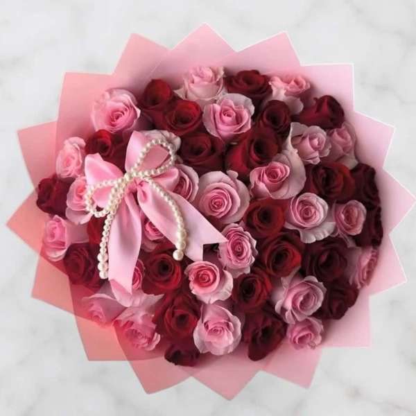 Bouquet of pink and red roses with a pink ribbon bow and pearl trim