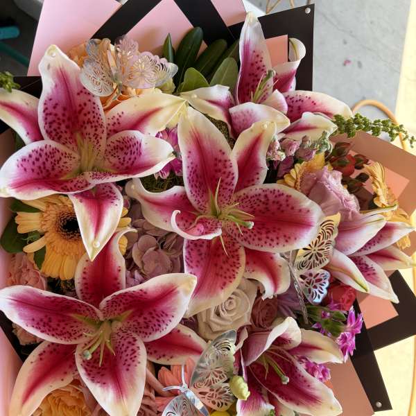 Bouquet of pink stargazer lilies, roses, and gerbera daisies with butterfly picks