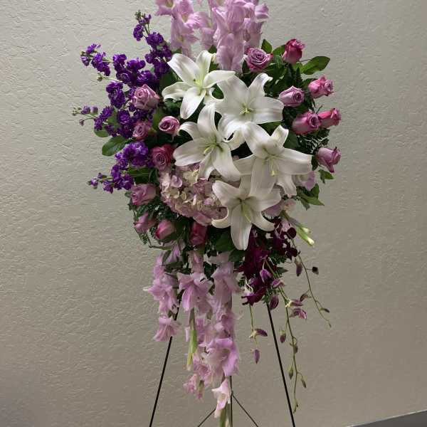 Tall standing floral spray with white lilies, pink roses, and purple blooms