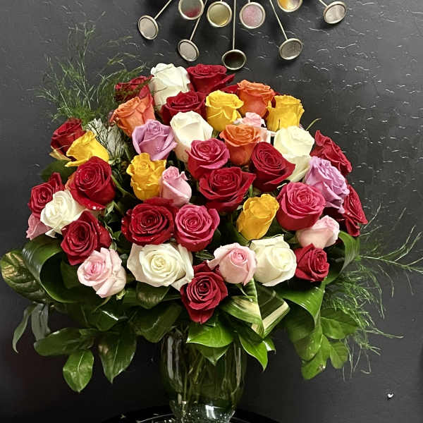 Mixed roses in a glass vase with glossy greenery