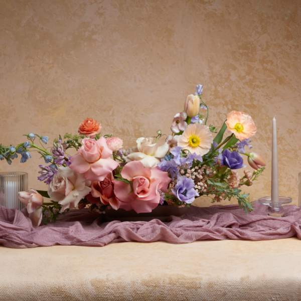 Low floral centerpiece with pink, white, and lavender blooms on a table