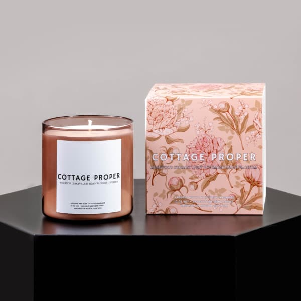 Rose-colored candle in a glass jar beside a floral-patterned box
