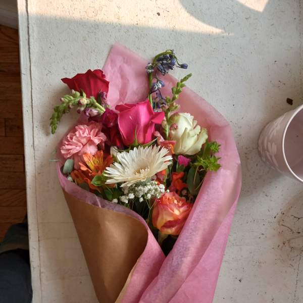 Mixed bouquet of roses, carnations, and a white daisy in pink wrapping