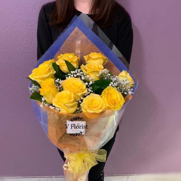 Bouquet of yellow roses wrapped in blue and clear paper