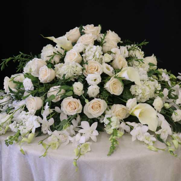 Large white floral casket spray with roses and calla lilies