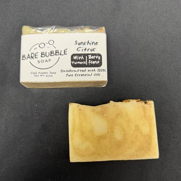 Bar of handmade soap in a labeled wrapper beside an unwrapped soap bar