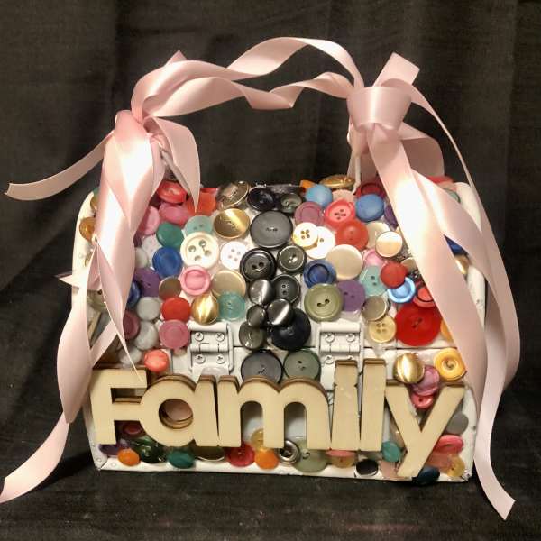Decorative basket filled with colorful buttons and a pink ribbon bow