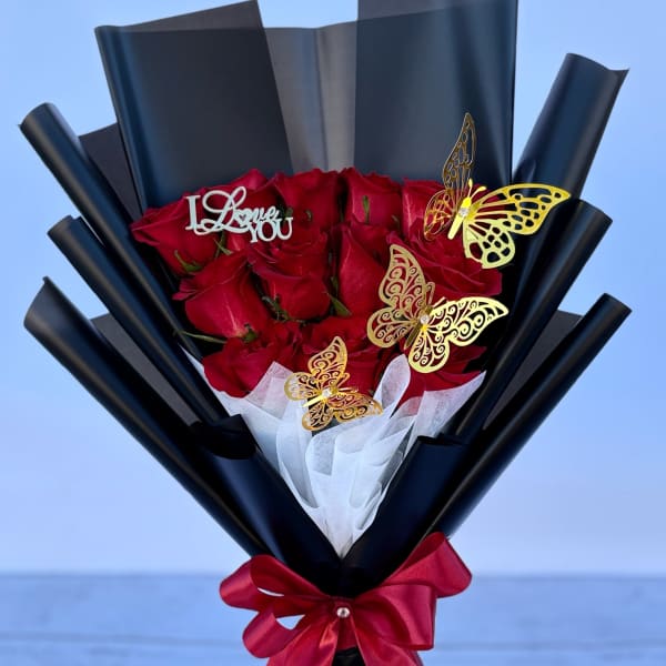 Bouquet of red roses wrapped in black paper with a red ribbon