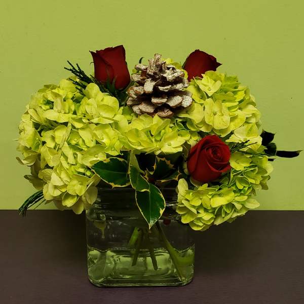 Yellow hydrangea arrangement with red roses in a glass vase