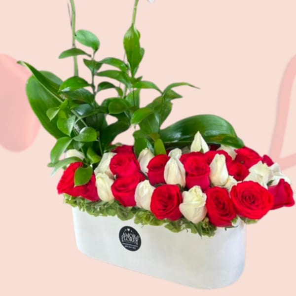 White orchids rise above red and white roses in a white box arrangement.