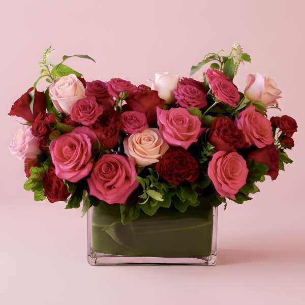 Pink and red roses arranged in a square glass vase