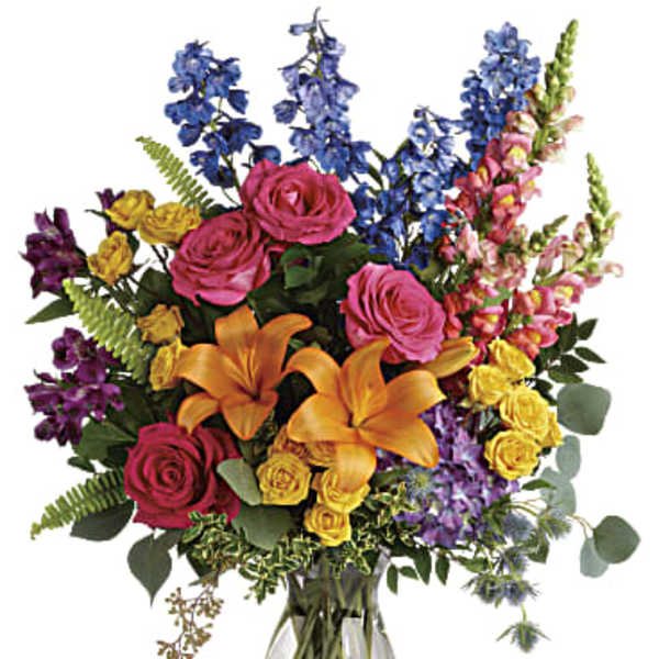 Colorful bouquet of roses, lilies, and delphinium in a glass vase