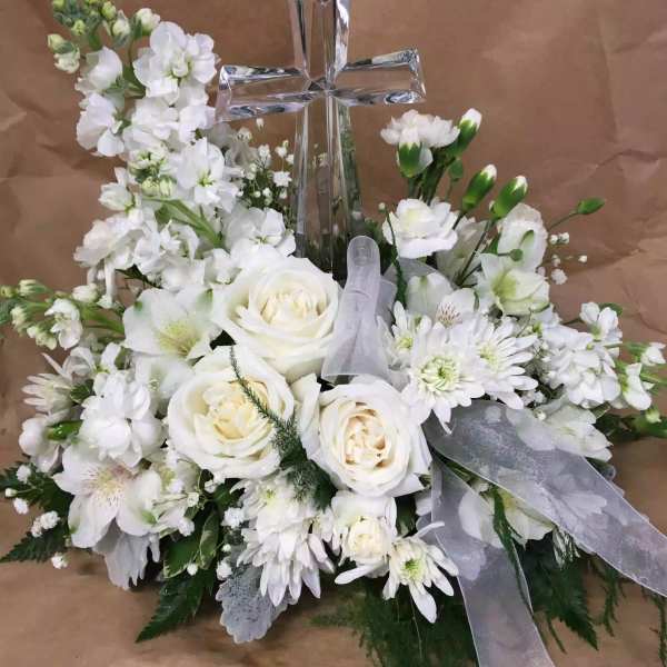 White floral arrangement with a clear cross centerpiece and sheer ribbon