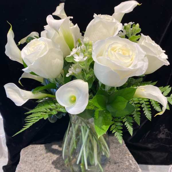 White roses and calla lilies in a clear glass vase