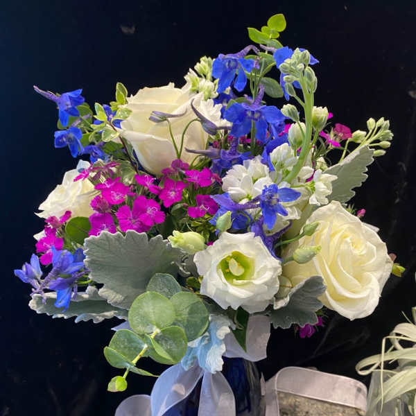 Bouquet of white roses, blue flowers, and pink dianthus in a blue vase
