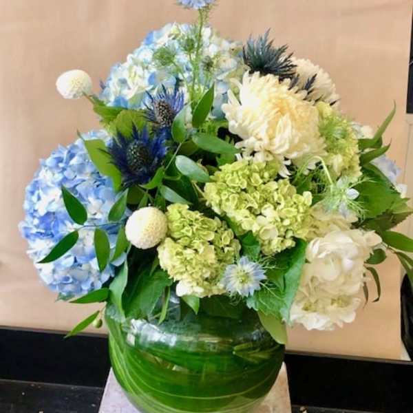 Blue and white floral arrangement in a green glass vase