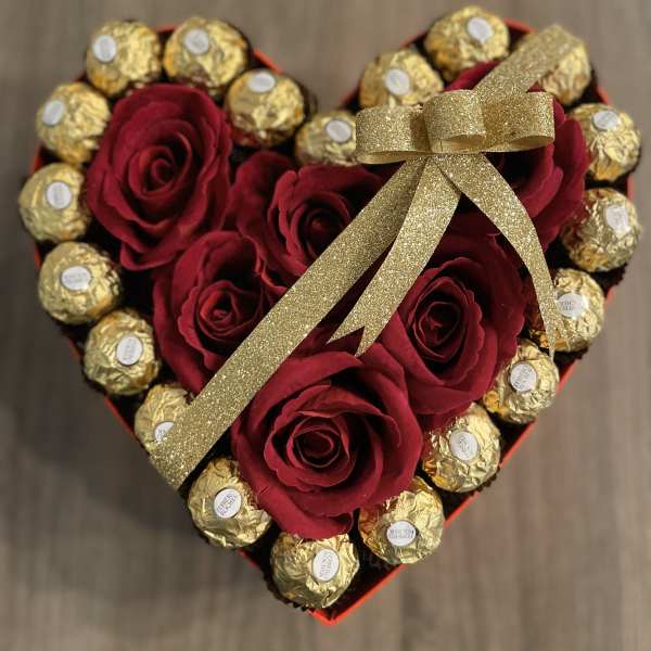 Heart-shaped box with red roses and gold-wrapped chocolates tied with a gold ribbon