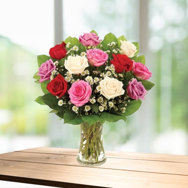 Bouquet of red, pink, and white roses in a clear glass vase