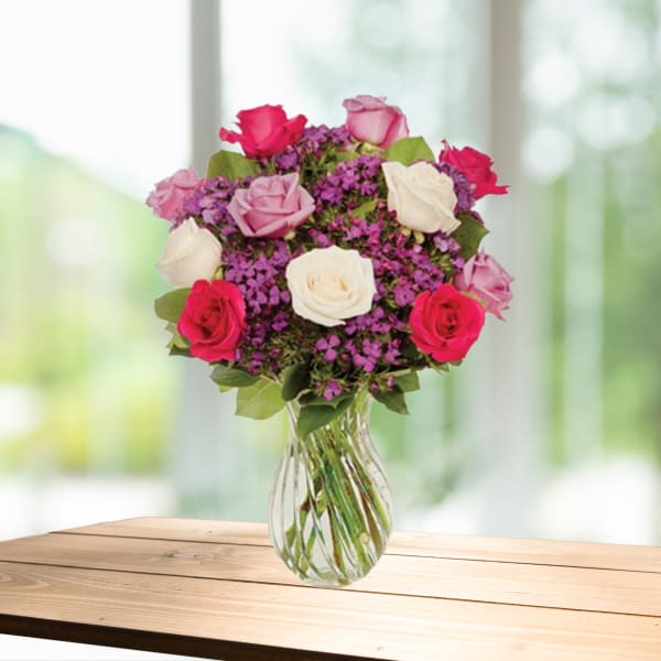 Bouquet of pink, white, and red roses in a clear glass vase