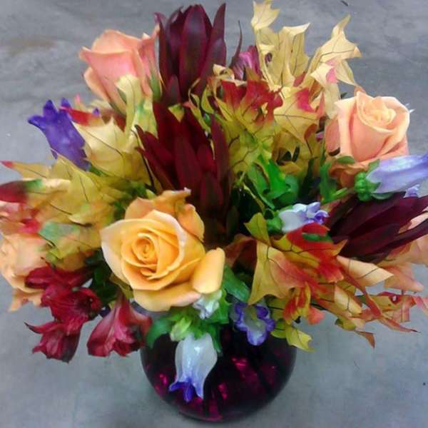 Bouquet of multicolored roses and tropical flowers in a dark vase