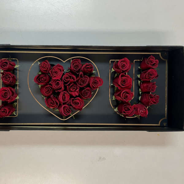 Red roses arranged to spell "I ♥ U" in a black tray