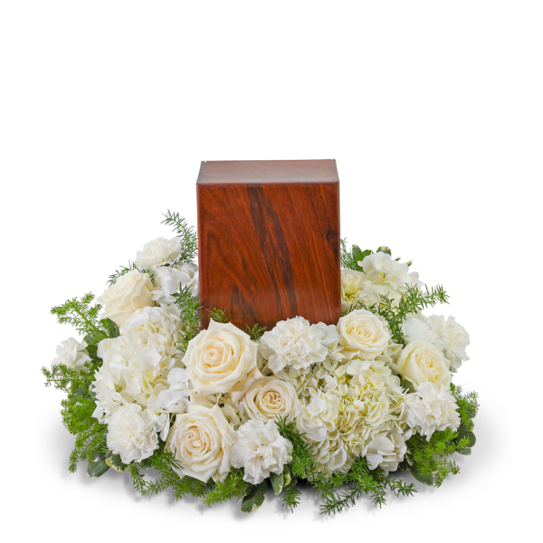 White roses and carnations surround a wooden urn.