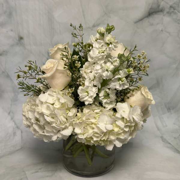 White roses and hydrangeas arranged in a glass vase