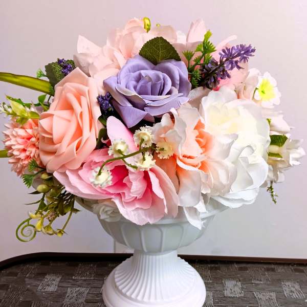 Artificial pastel rose bouquet in a white pedestal vase